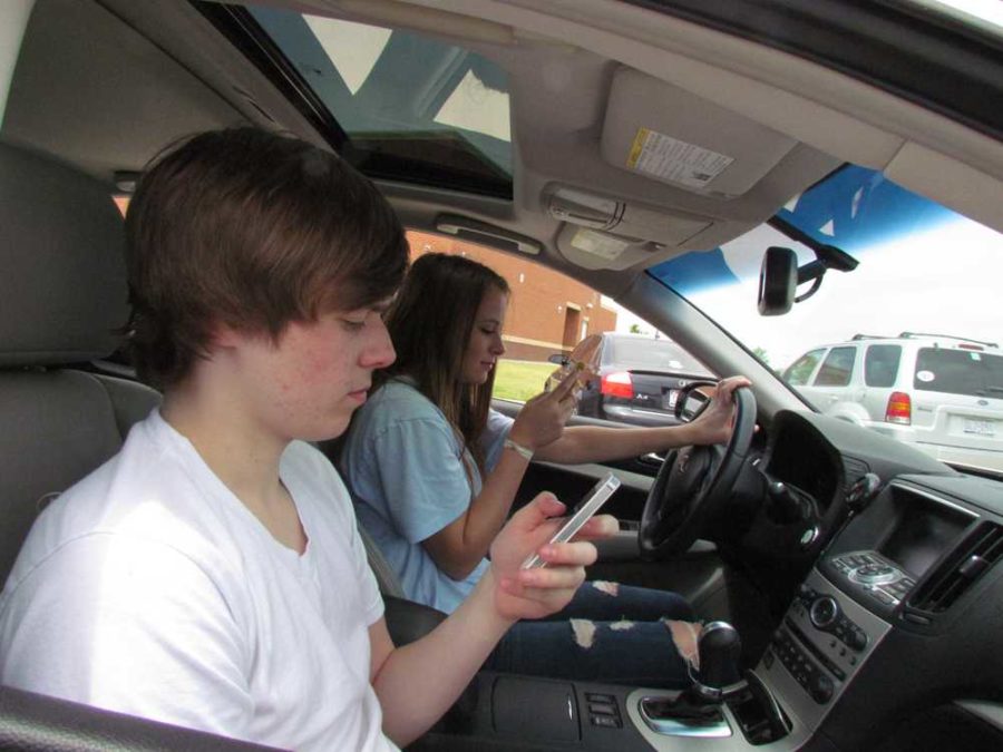 Sophomores Michael Jones and Clare Keil are both on their phones will driving through the parking lot.