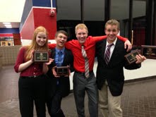 Debate team members Bryce Broomham, Nate Wutzke, Avery Flessner, and Emma Holmes present their trophies. 