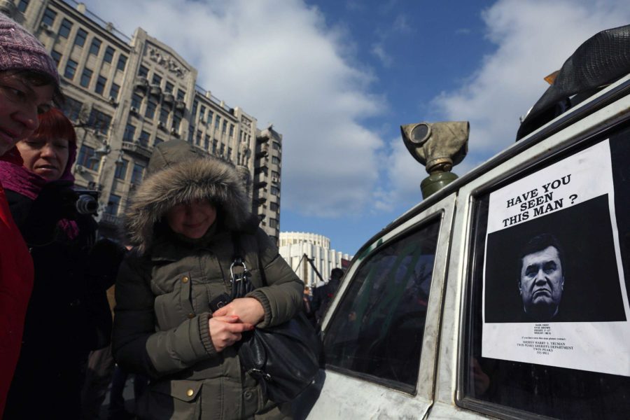 The interim government of Ukraine put their deposed President Viktor Yanukovich on a wanted list Monday, Feb. 24, 2014. Women in Khreshchatik street look at an image of Yanukovich.