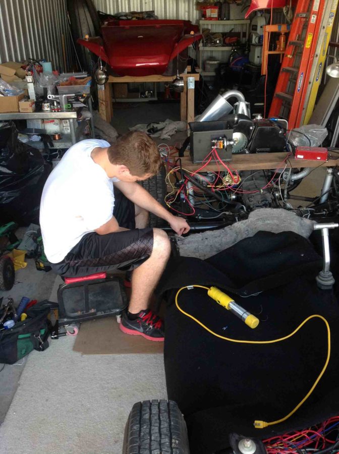 After sitting in his garage untouched for years, senior Joe Whitman works on the interior carpet of his VW Dune Buggy as part of his senior project.