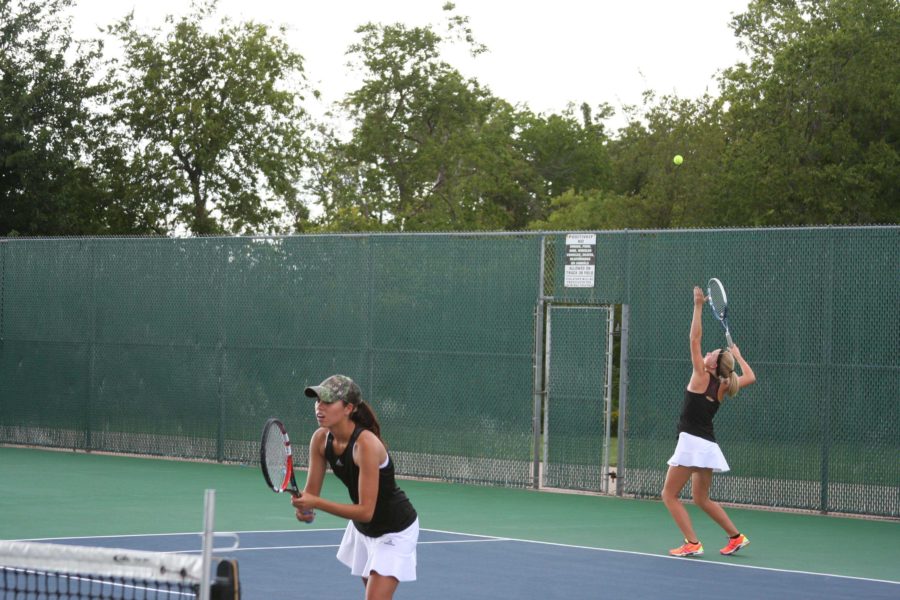 Senior Anna Dickens and Sophomore Ariaan Cnossen serve against their opponent while playing doubles. 