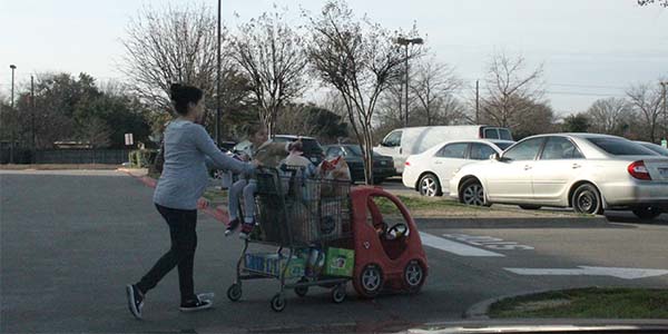 A woman exiting Kroger is carrying her items in plastic bags. If this were in Dallas, she would have to pay a fee to use such bags. 