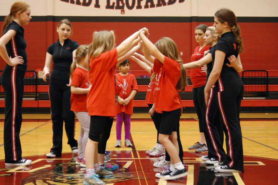 Elementary aged girls practice their tunnel dance move for their performance.
