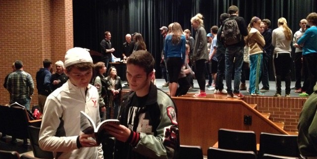 Juniors and cross country runners Jacob Myers and Brock Bittner flip through the book Running the Edge after getting it signed by the authors at the presentation in the auditorium. 