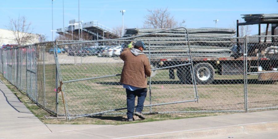 A member of the construction team installs fencing to keep students out of the construction areas.