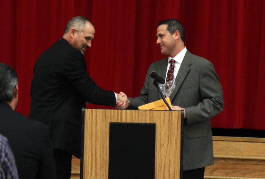 New head football coach Todd Ford receives his contract from principal Chris Mayfield after being confirmed by the school board on Wednesday night.