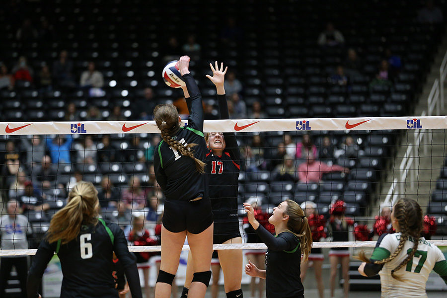 Junior Allie Moger jumps above net to block her opponent's spike.