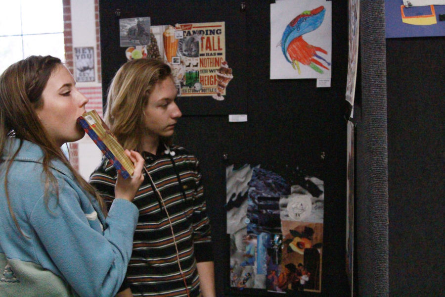 Senior John Stalling And Sophia Desjardins hanging up middle school art work. 