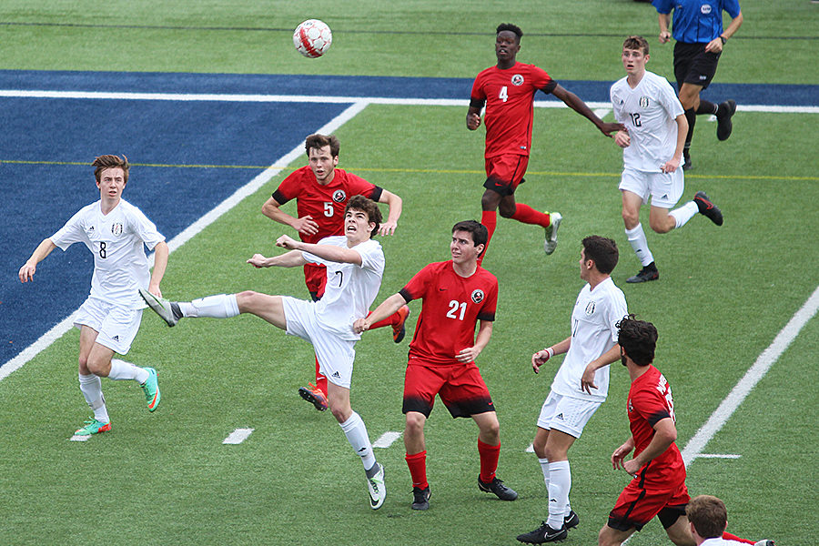 Sophomore Benji Merrick heads the ball around the Colleyville Heritage defenders to Seniors Evan Cantor and Cal Cranfil.