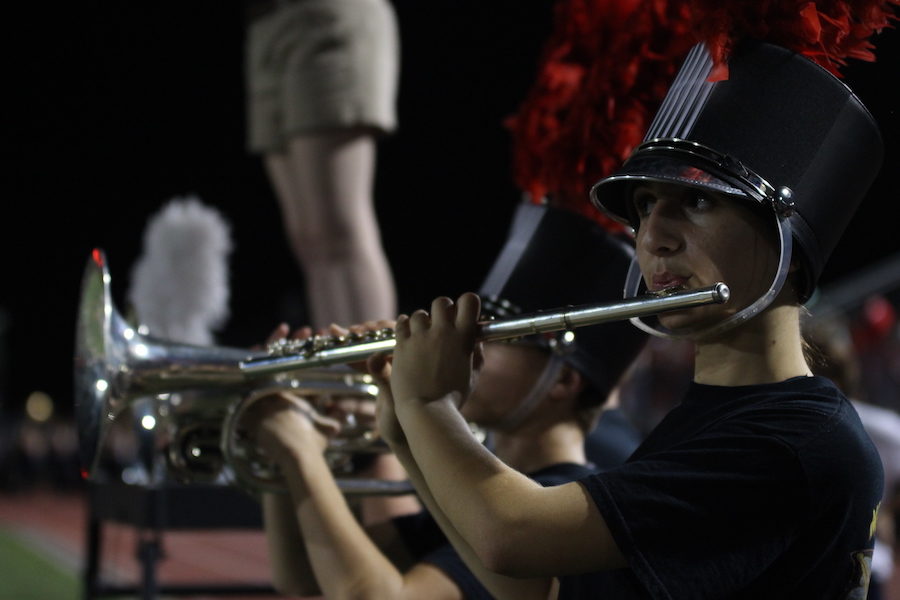 Freshman Avae Odza plays the flute at the front of the field facing the rest of the band members. 
