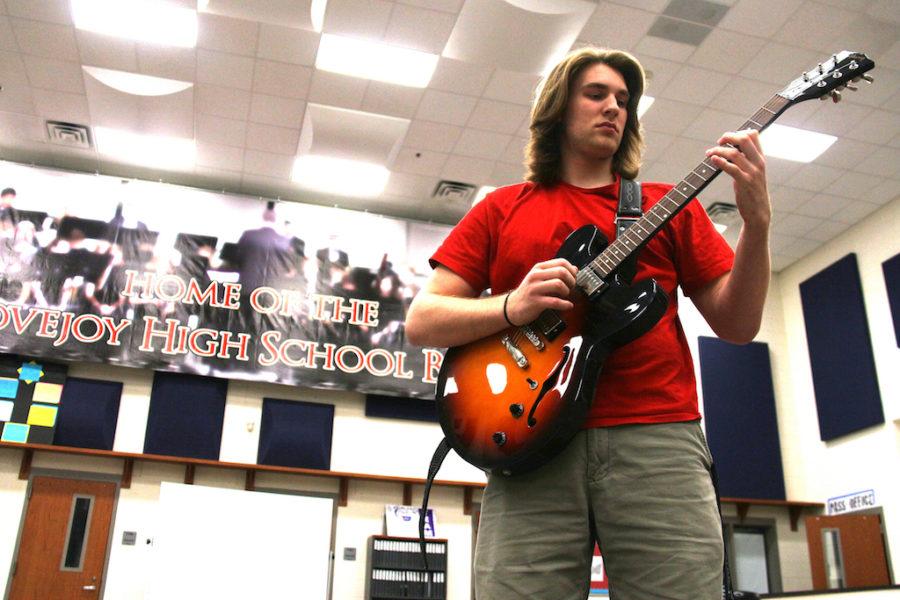 Jack practices on his guitar in the band hall during jazz band rehearsal.