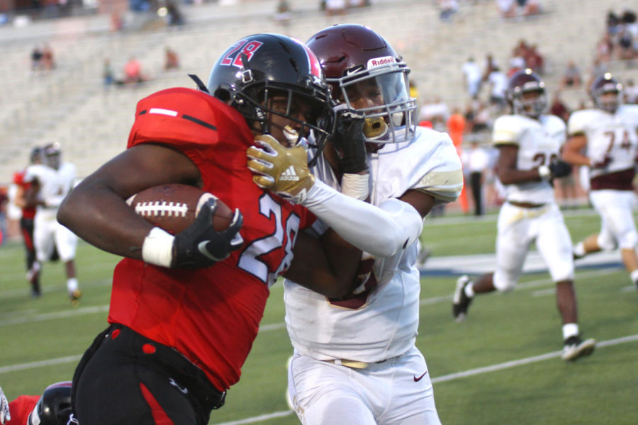 Senior Jahi Rainey fends off a Heritage defender with a stiff arm.