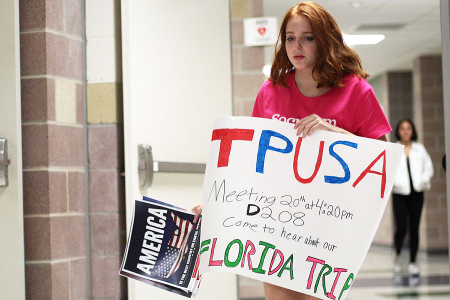 Sophomore Ariel Feldman hangs posters for the new Turning Point USA club before school on Wednesday, Sept. 12.