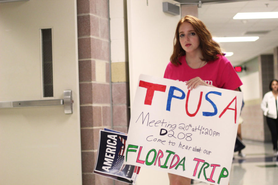 Sophomore Ariel Feldman hangs posters for the new Turning Point USA club before school on Wednesday, Sept. 12.