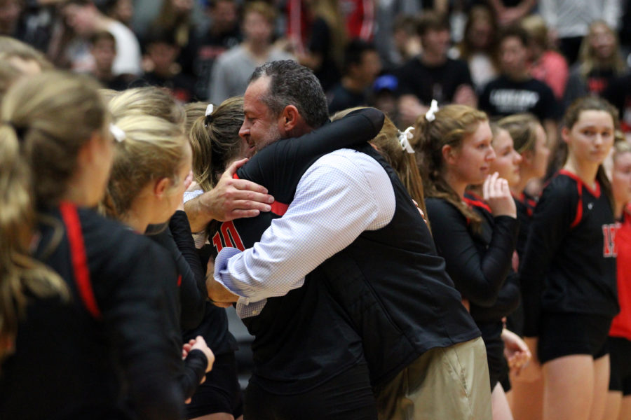 Head coach Jason Nicholson hugs senior Madison Waters as the team lines up on the court after the game.