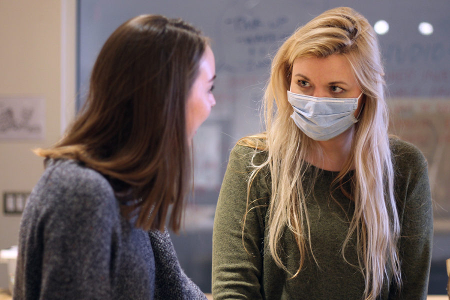 Art teacher Amanda Beller chats with senior Mallory Sailer in room E113 during eighth period on Thursday. Beller wore a mask during her classes this week as a precaution against the flu. 