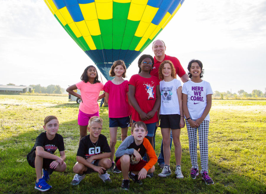 Former Puster Principal Kevin Parker poses with elementary school students prior to his hot air balloon ride. Every summer the librarian, Alison Smithwick, puts together a reading goal, so if the kids read for so many minutes or so many books at the end of the school year, she promises the kids I will do something, Parker said. ...This year, I am terrified of heights, so I went up in a hot air balloon.