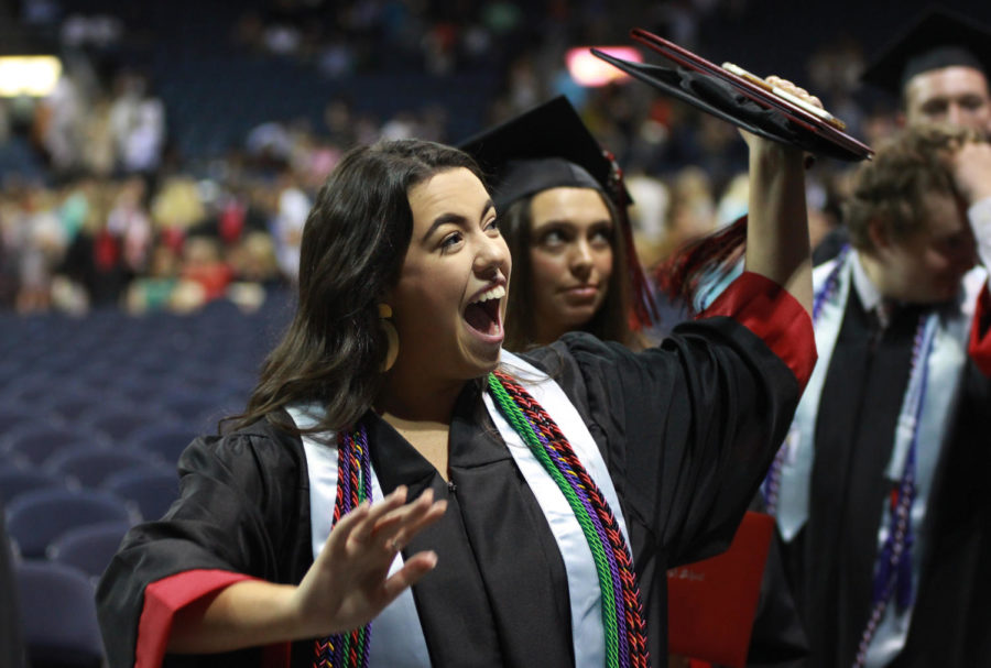 Graduate Riley Bergwell waves ecstatically to her friends and family as she leaves the event center floor to receive her diploma from backstage. 
