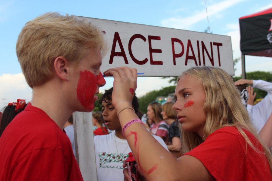 Sophomore Avery Templin paints her brother, Karson Templins face all red for red out. Girls soccer hosted the face painting booth.
