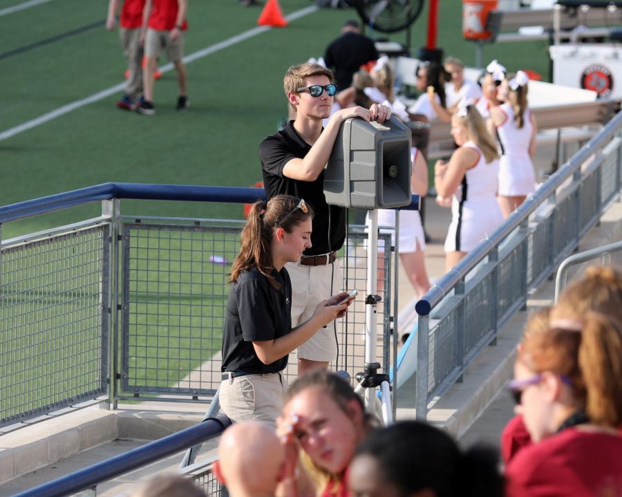 Seniors Lily Hager and Joe Harris set up the directors voice speaker at a football game. Two to three speakers are brought to every practice and performance for the directors voice or for the metronome.