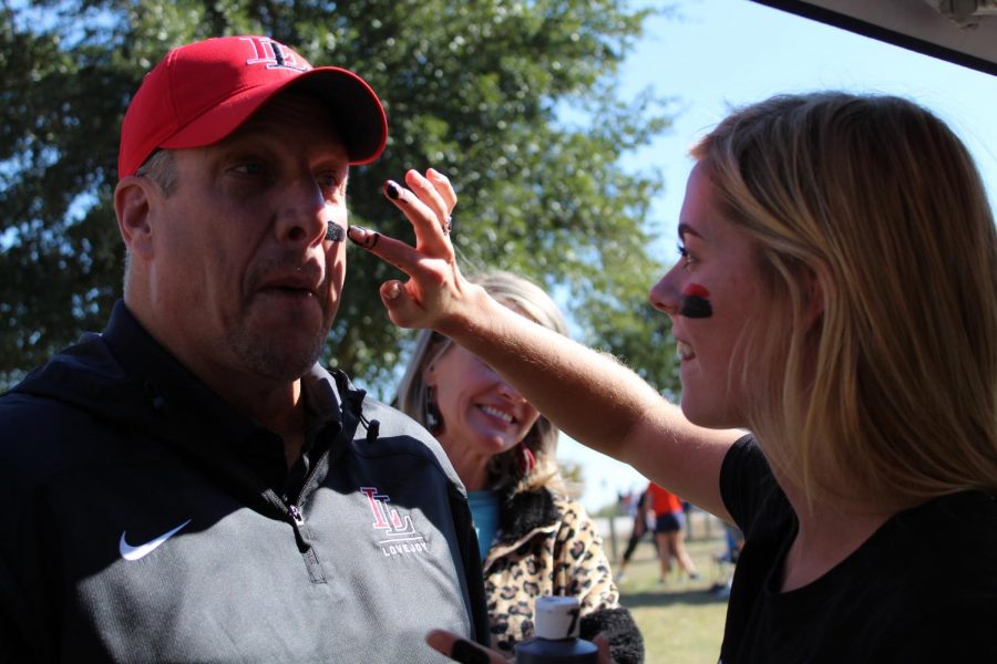 Senior Sara Rouse applies face paint to Superintendent Michael Goddard. Goddard later posted a selfie with students supporting runners at the meet who also wore paint to show spirit. 