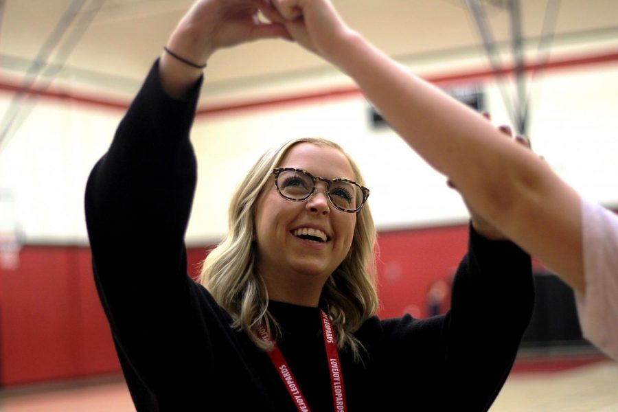 New JV cheer coach and leadership teacher Laura Pikl corrects a cheerleaders arm positioning. Before coming to the high school, she taught in Oklahoma.