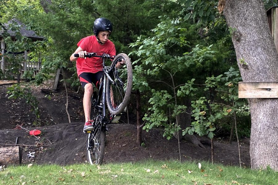 Sophomore Luke Farkas pops a wheelie after riding up a hill. It took Farkas about 50 hours to build the course. 