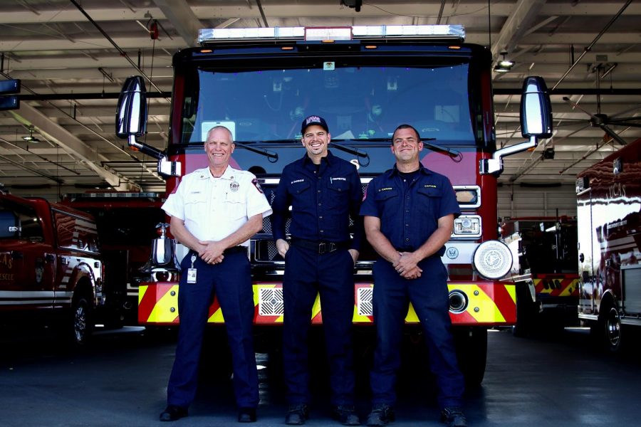 Fire Chief Ted Stevens, Fire Captain Ethan Carver, and Paramedic Michael Dunnam stand at the front of one of their fire engines inside their station. The three work together for the Lucas Fire Department. 