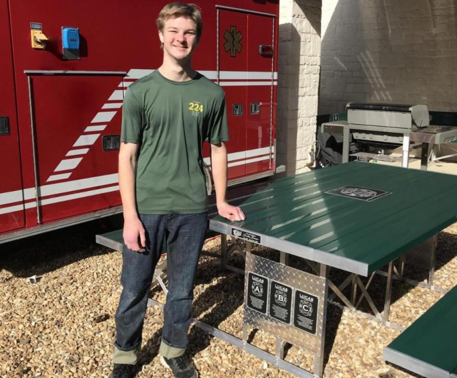 Sophomore Dawton Bruner stands next to the table he built and donated to the Lucas Fire Department. Bruner received his Eagle Scout for the project.