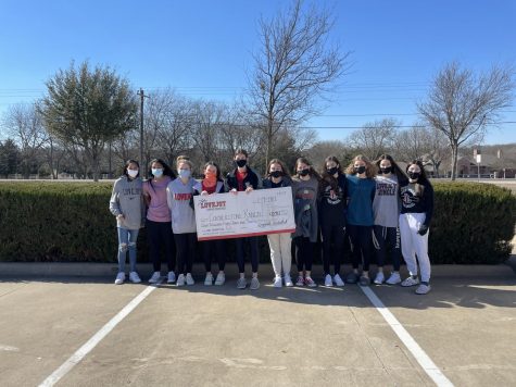 Girls basketball players hold the check made out to Cornerstone Ranch by the basketball booster clubs. The check is for a sum of $8,043.41.