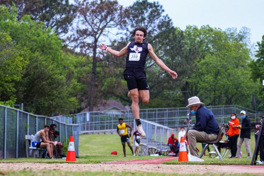 Freshman long jumper Colston Adamson leaps into the pit on his fourth jump. Adamson placed seventh overall with a 21-01.50 meter jump.
