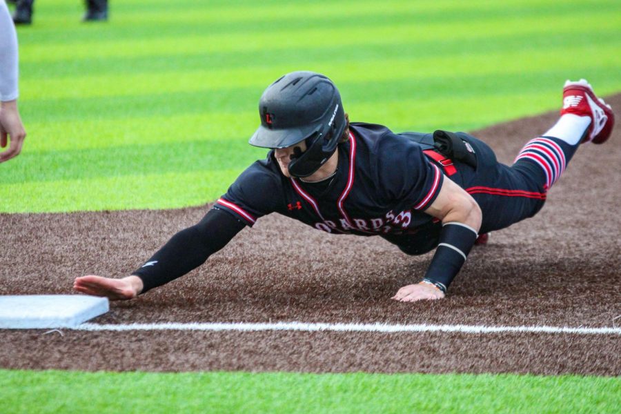 Freshman right fielder no. 23 Matthew Mainord dives back safely to first base on a pickoff attempt by Rockhill’s junior pitcher no. 1 Brett Foss. Mainord reached base after a blooper hit single to left center field.
