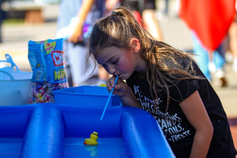 A young girl uses a straw to blow a rubber duck to the finish line. In the game, you have to move the duck to the end faster than your opponent to win.