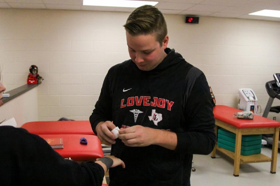 Athletic trainor Andrew Smith wraps a student-athletes wrist. Smith is a new trainer to the school, as well as head trainer Sarah Seedle. 