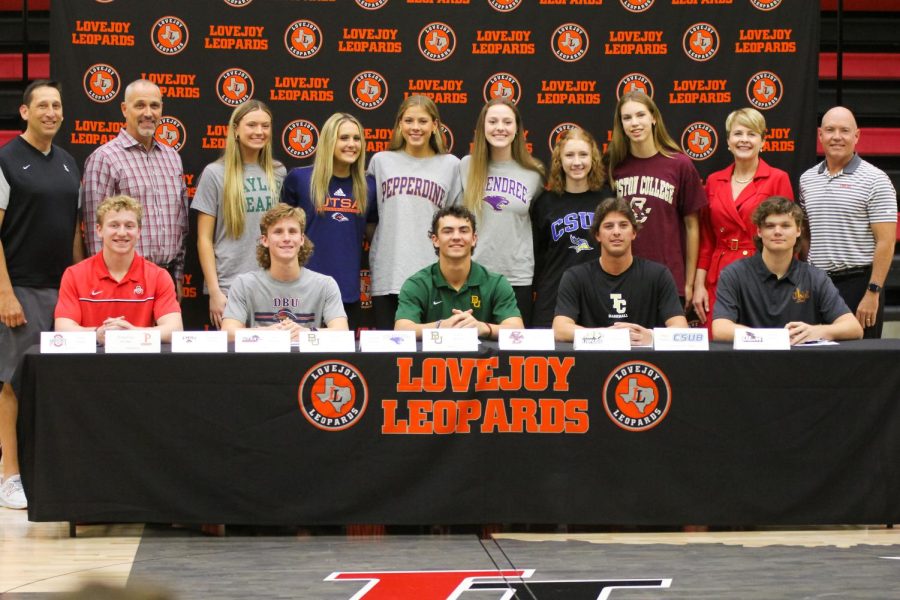 All eleven senior signees take a photo with coach Kyle Herrema, principal Chris Mayfield, superintendent Katie Kordel, and coach Chris Ross. The athletes represented four different sports.
