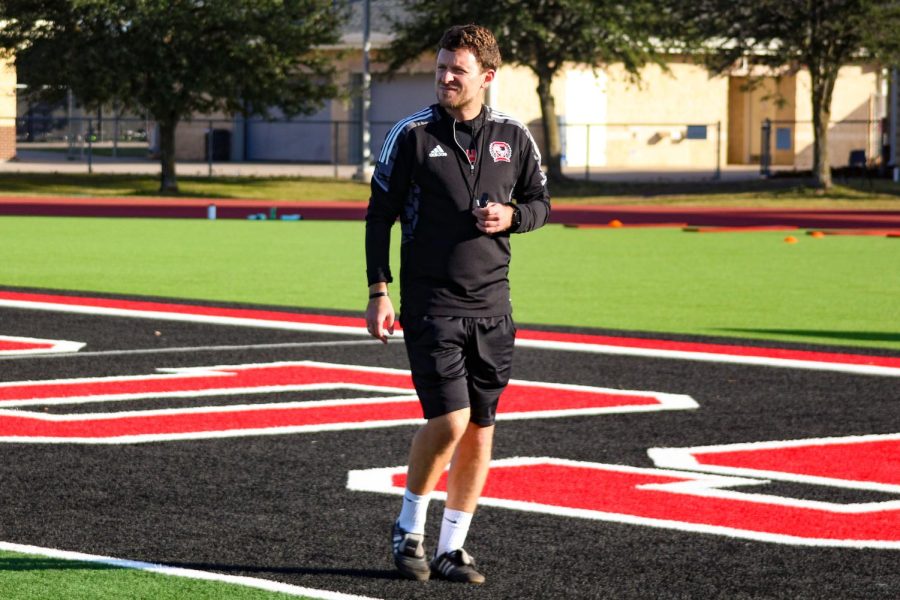 Head girls soccer coach Ian Keeble walks on the field as the team does warm-ups. After recovering from cancer last year, Keeble is ready to start coaching normally again.