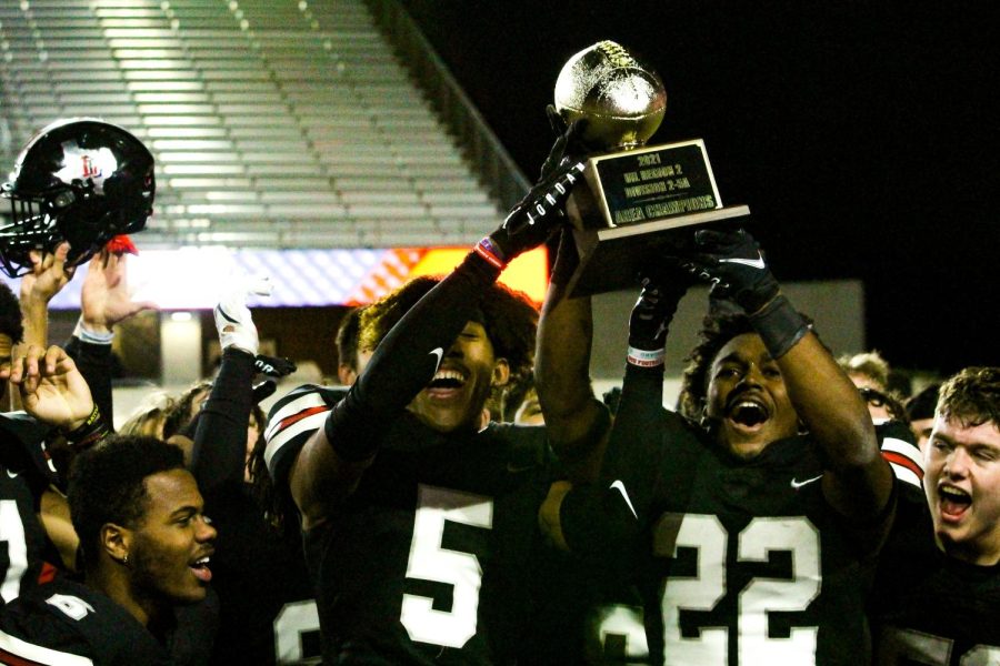 Senior defensive back no. 5 Jayden Lawton and junior defensive back no. 22 Roderick Mapps hold up the teams trophy. The football team was titled Area Champions for their win.