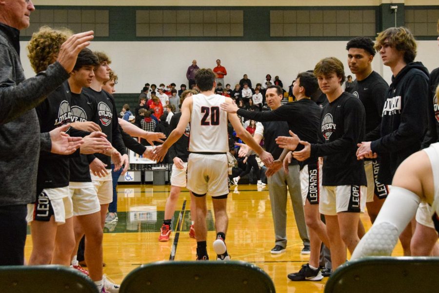 Senior shooting guard no. 20 Pete Peabody high fives his teammates as his name is announced at the start of the game. Peabody is a starter for the team.