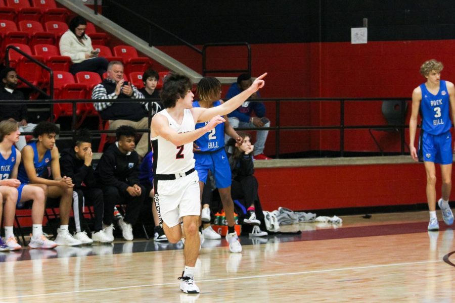 Senior safeguard no. 2 Jax Thompson signals a three-pointer was scored. Thompson scored 12 points in the game.