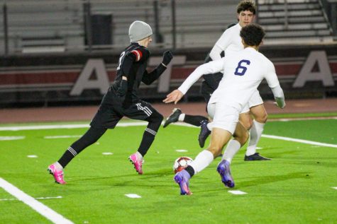 Junior no. 3 Caden Carlock dribbles the ball through two defenders. Carlock was also on the varsity soccer team last year.