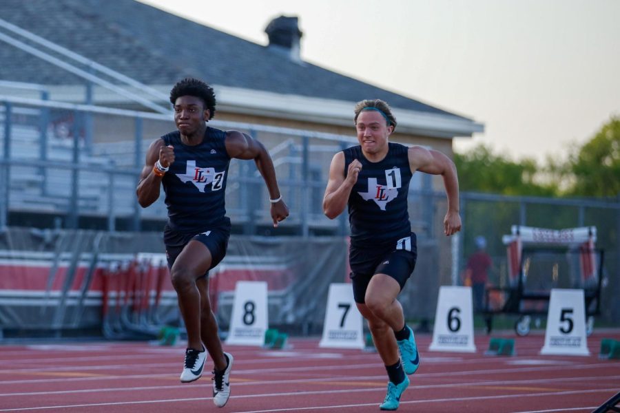 Juniors Kyle Parker and Mason Wallace mirror each others strides in the open 100 meter dash. Parker had a personal record dash with a time of 11.13.