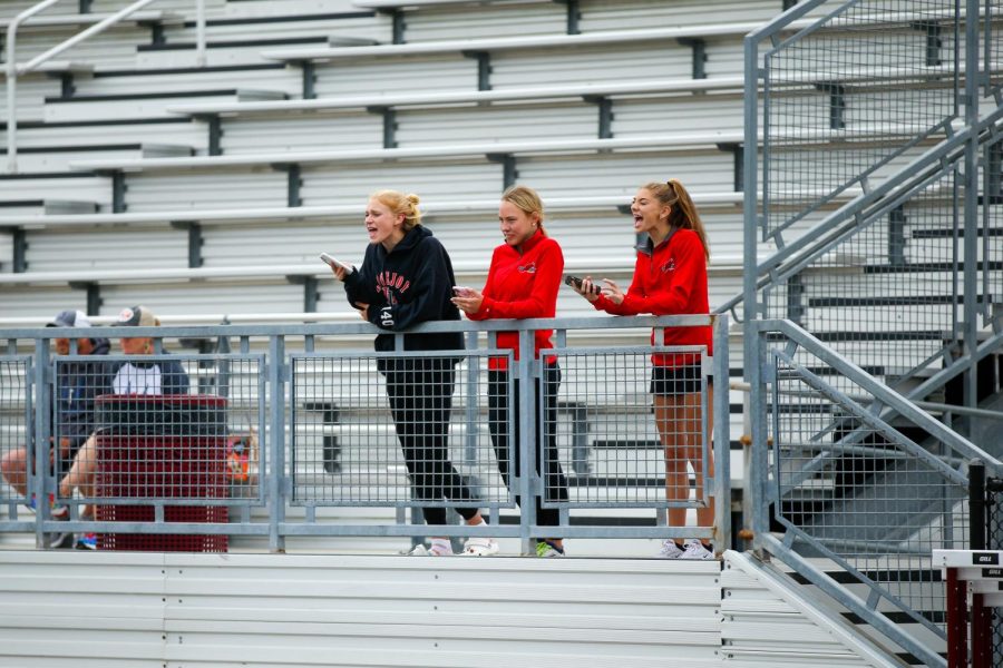 Sophomore Kailey Littlefield, senior Katie Armstrong, and sophomore Peyton Benson cheer on sophomore Sara Morefield and junior Amy Morefield in the 3200 meter race. The sisters placed first and second.