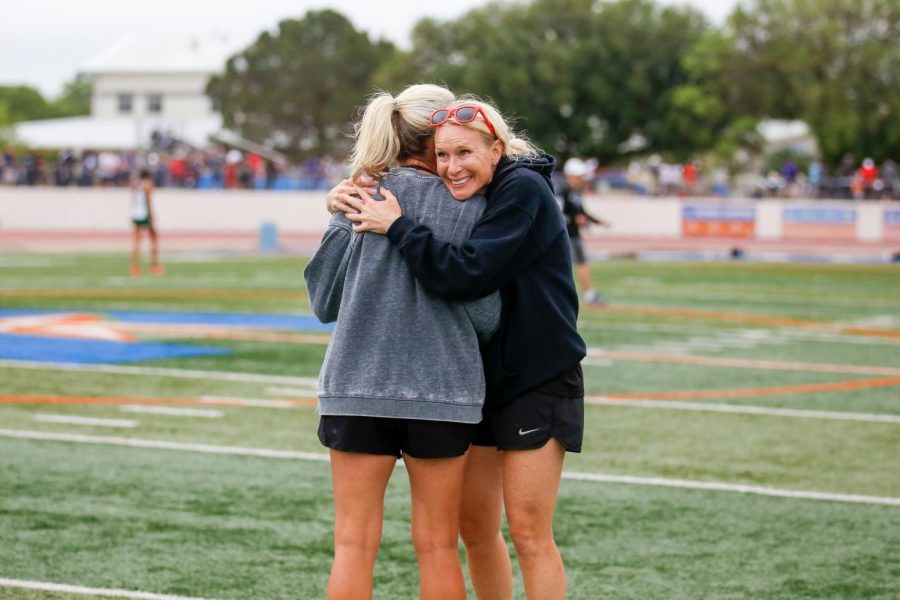 Head girls coach Carly Littlefield hugs coach Traci Benson after the conclusion of the 3200 meter race. The girls placed top two, qualifying them for state. 