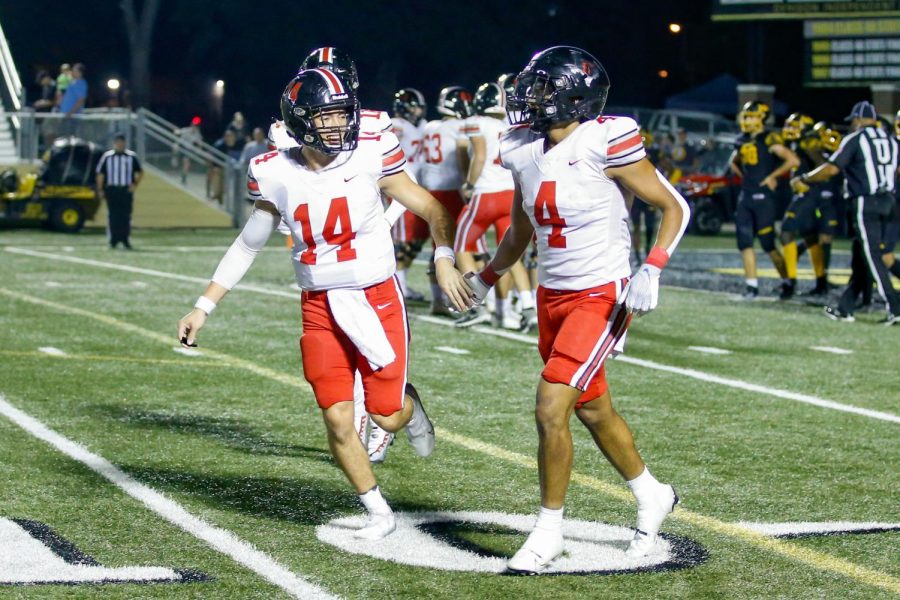 Senior quarterback no. 14 Austin Gonzalez high fives junior running back no. 4 Dante Dean after a touchdown. In the previous play, Gonzalez handed the ball off the Dean, and Dean ran it into the end zone.