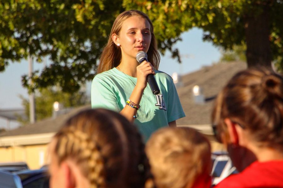 A girl sings karaoke at the choir booth. Choirs A Cappella group performed at the community pep rally in the parking lot before the game.