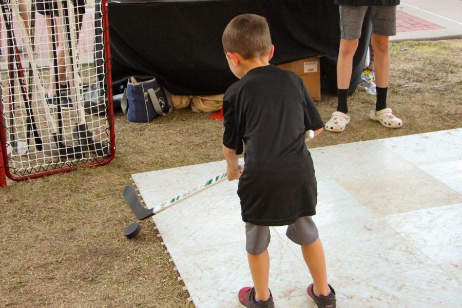 A young boy hits a puck into the goal at the Hockey booth for Leopard Friday. The hockey team is ranked no. 1 in the state.