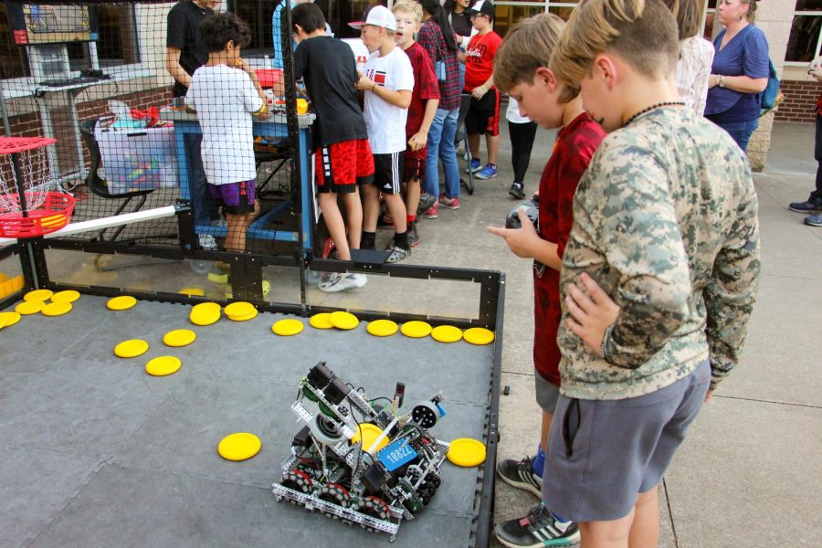 A young boy plays a game at the robotics station. The goal was to shoot the yellow disks into the target.