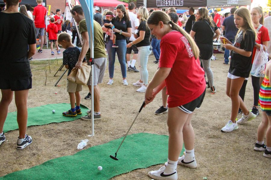 A girl puts a golf ball at the golf booth. Golf has their fourth match of the season on Nov. 4.