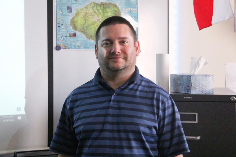 John Baker stands in front of a map of Kauai, Hawaii. Baker teaches AP Psychology at the high school. 