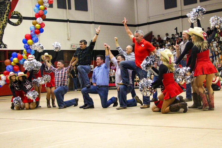 Senior cheerleaders and their dads pose at the end of a dance routine. The dance is an annual performance at the senior pep rally. 